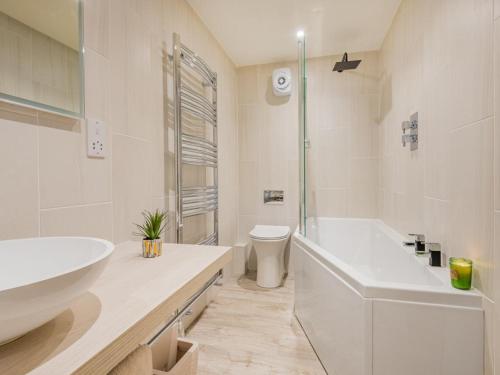La salle de bains blanche est pourvue d'une baignoire, d'un lavabo et de toilettes. dans l'établissement 3 Bed in Borrowdale SZ465, à Rosthwaite