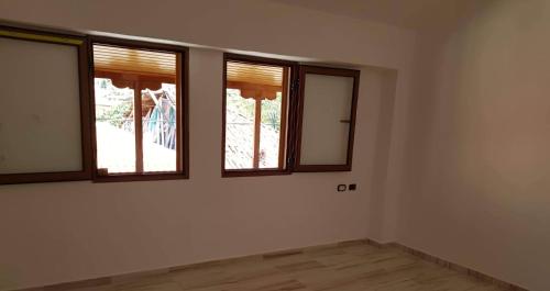 um quarto vazio com 3 janelas e pisos em madeira em Villa lake ohrid em Pogradec