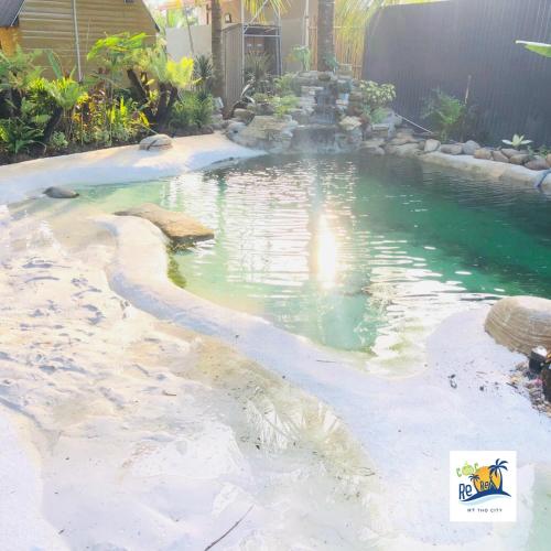 a swimming pool with a fountain in a backyard at Cóc Retreat Mỹ Tho City in My Tho