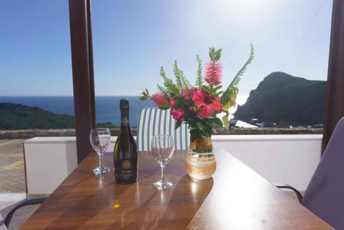 a table with two wine glasses and a vase with flowers at Galini Apartments in Léntas