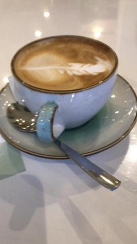 a cup of coffee on a plate with a spoon at Hotel Macavi Playa in Rota