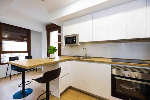 eine Küche mit weißen Schränken und einer Holzarbeitsplatte in der Unterkunft Apartamentos turísticos Plaza sevillano , by CartagenaSpain in Cartagena