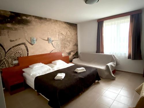 um quarto de hotel com uma cama com duas toalhas em Ligetalja Termál Hotel em Penészlek