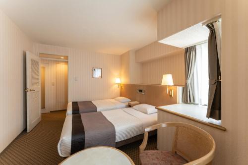 a hotel room with two beds and a window at HOTEL MYSTAYS Kanazawa Katamachi in Kanazawa