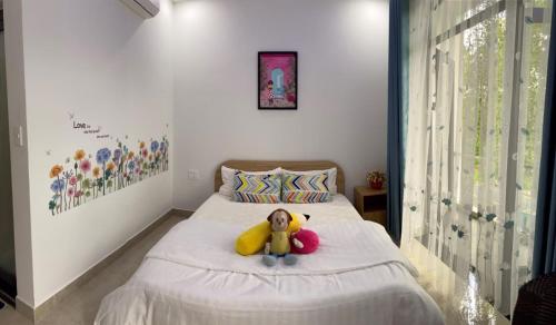 a teddy bear sitting on a bed in a bedroom at LA GAI HOMESTAY HOI AN in Hoi An