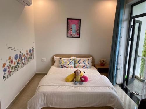 a teddy bear sitting on a bed in a bedroom at LA GAI HOMESTAY HOI AN in Hoi An