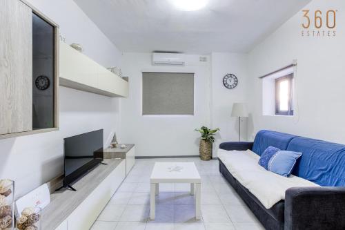 een woonkamer met een blauwe bank en een tv bij Peaceful 1BR maisonette with Sofa Bed with WIFI by 360 Estates in St Paul's Bay
