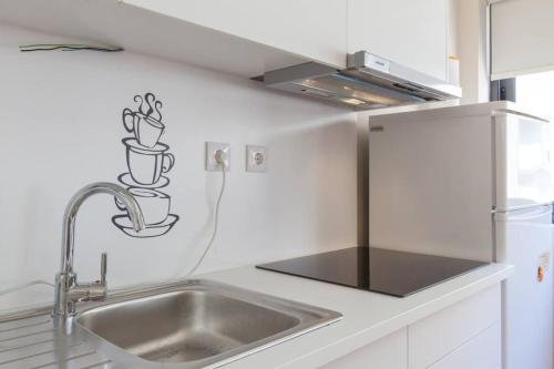 a white kitchen with a sink and a refrigerator at Picaria - Orange in Porto