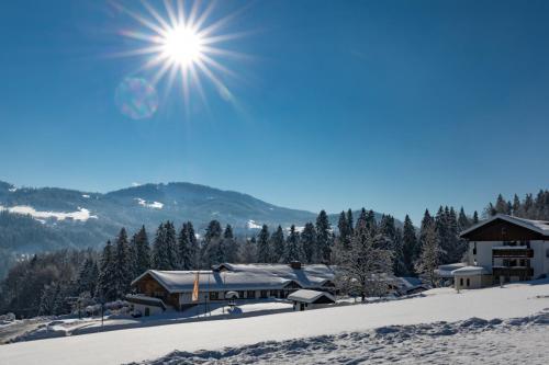 a building in the snow with the sun in the sky at MONDI Resort und Chalet Oberstaufen in Oberstaufen