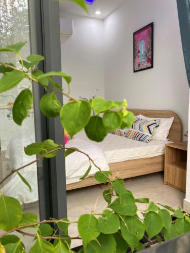 a bedroom with a bed and a plant in the foreground at LA GAI HOMESTAY HOI AN in Hoi An