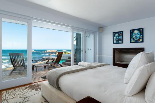 a bedroom with a bed and a balcony with the ocean at Sea Haven - Bakoven Beach Front Villa in Cape Town