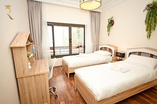 アブダビにあるBeach bliss 3BR apartment Cornicheのベッド2台と窓が備わるホテルルームです。