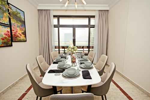a dining room with a white table and chairs at Elegant 3BR Retreat - Corniche Luxe Escape in Abu Dhabi