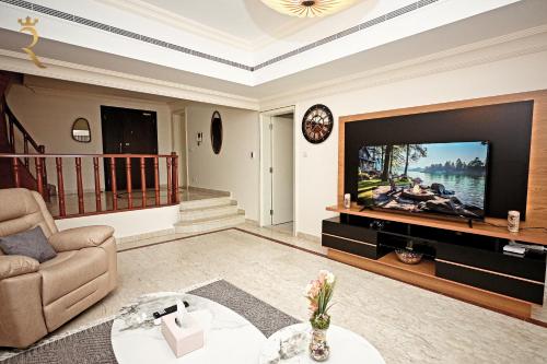 a living room with a large tv and a couch at Elegant 3BR Retreat - Corniche Luxe Escape in Abu Dhabi