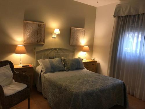 a bedroom with a bed and a chair and two lamps at Hotel Macavi Playa in Rota