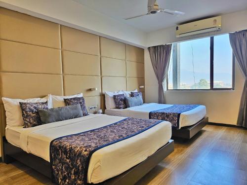 um quarto de hotel com duas camas e uma janela em Yashshree Milestone em Siliguri