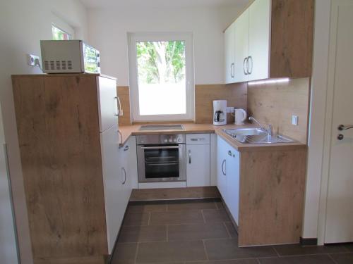 a small kitchen with white cabinets and a window at Ferienhauspark Asgard in Damp in Damp