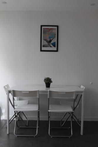 une table et des chaises blanches avec une photo sur le mur dans l'établissement La Locomotive- SPA - 400 m de la plage, à Sausset-les-Pins