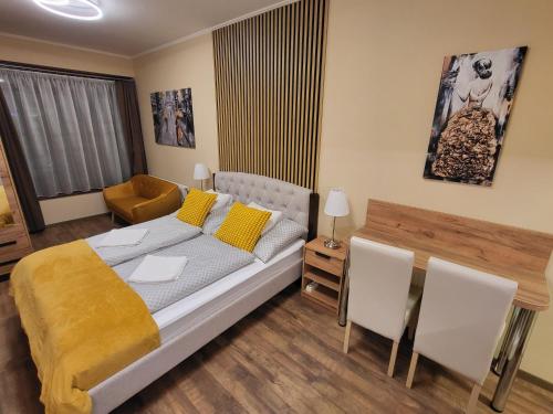 1 dormitorio con 1 cama, mesa y sillas en Glória Apartman Szarvas, en Szarvas