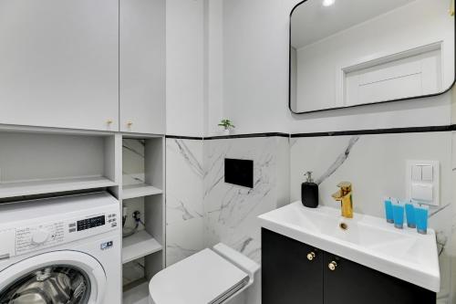 a white bathroom with a washing machine and a sink at Comfort Apartments Złotników in Gdańsk