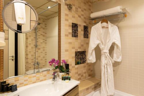 een badkamer met een witte badjas aan een muur bij Elite Resort & Spa in Manamah
