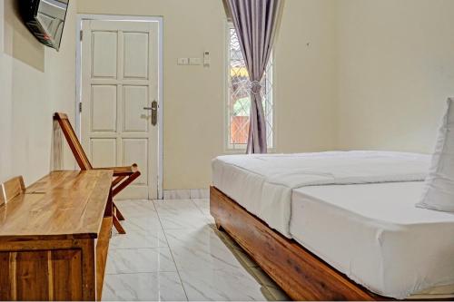 a bedroom with a bed and a desk and a window at Capital O 93345 The Saka Guest House Syariah in Bandar Lampung