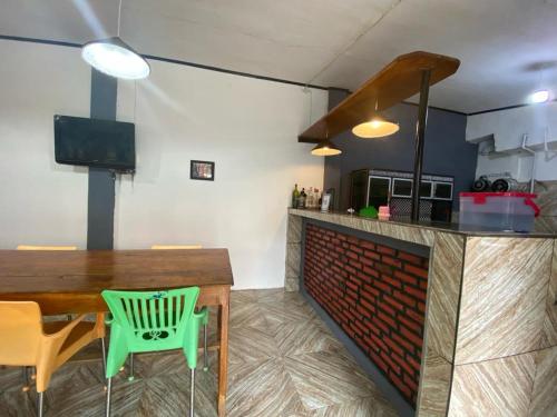 a kitchen with a table and a green chair at Krui Saejadi Surf and Stay in Krui