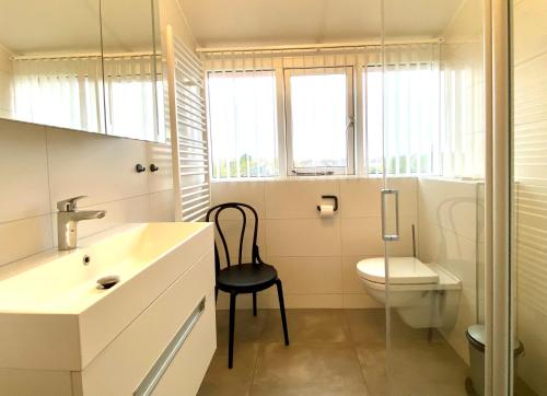 a bathroom with a toilet and a sink and a chair at Kustverhuur, Park Scheldeveste Zwin 010 in Breskens