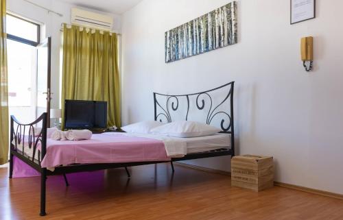 a bedroom with a bed with pink sheets and a tv at By the sea West Apartments in Kaštela