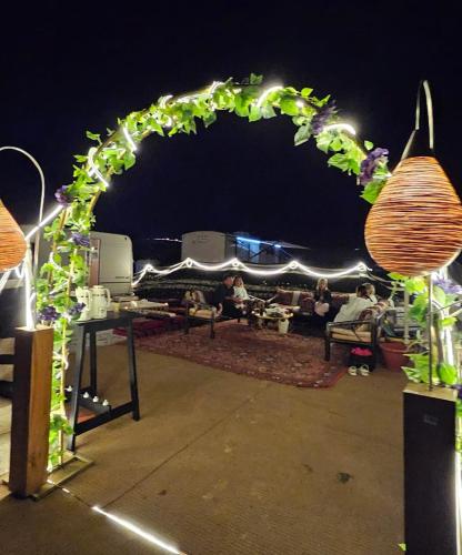 a lit up arch with people sitting under it at night at Al khateem Motor Home in Liwa