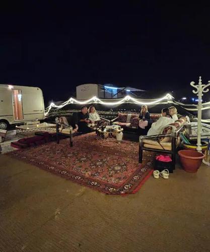 un gruppo di persone seduti su panchine in un parcheggio di Al khateem Motor Home a Liwa