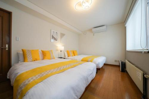 two beds in a room with yellow and white at Canal Villa Otaru - Vacation STAY 99697v in Otaru