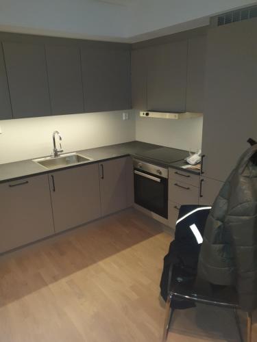 a kitchen with grey cabinets and a sink and a chair at Cosy 1bedrom apartment in Lorenskog