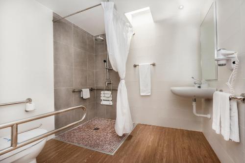ein weißes Bad mit einer Dusche und einem Waschbecken in der Unterkunft Kn Aparthotel Columbus in Playa de las Americas