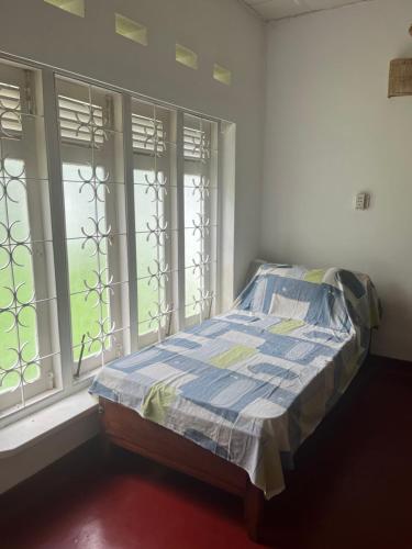 a bed sitting in a room with a window at Unrushed Midigama in Midigama