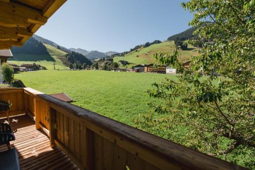 a deck with a view of a large green field at Winkler Appartements in Saalbach-Hinterglemm