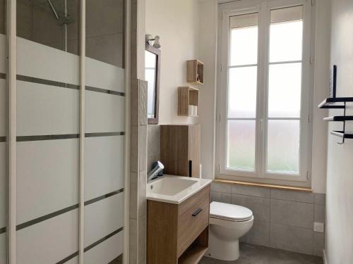 a bathroom with a toilet and a sink and a window at Le Clos Aime in Contres