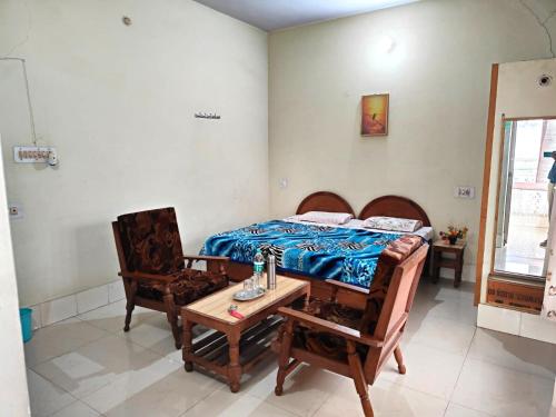 a bedroom with a bed and two chairs and a table at Hotel Spoonbbill in Bharatpur