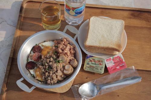 a table with a bowl of food and a plate of bread at Eden House Resort in Nakhon Nayok