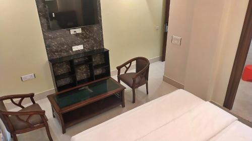 a room with a bed and two chairs and a tv at Hotel Blue Moon Deluxe A Breathtaking stay in Prayagraj