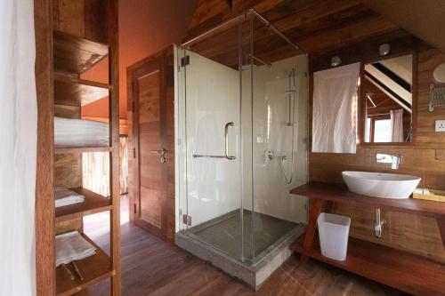 a bathroom with a glass shower and a sink at Treellion Jungloo in Phnom Penh
