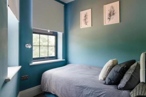 a blue bedroom with a bed and a window at OYO Ruby Pub & Hotel in Brighton & Hove