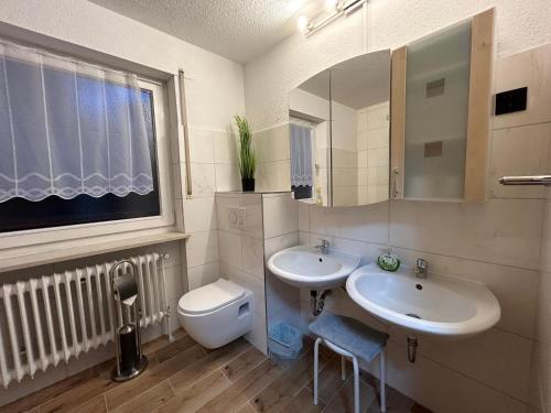a bathroom with two sinks and a toilet and a window at Ferienwohnung Zucker in Grafenau