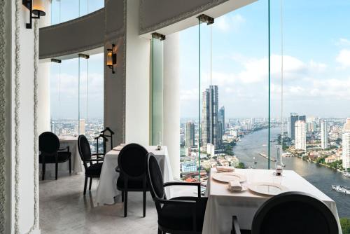 a restaurant with tables and chairs and large windows at lebua at State Tower in Bangkok