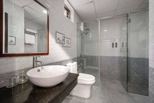een badkamer met een wastafel, een toilet en een douche bij Seagull Nest Hoi An Beach Village in Tân Thành (1)