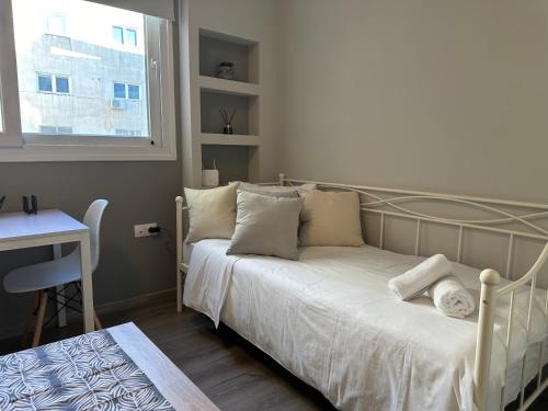 a bedroom with a bed with white sheets and a window at Work from home Project in Thessaloniki