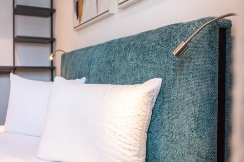 a bed with white pillows and a green headboard at lechner living apartments in Wald im Pinzgau