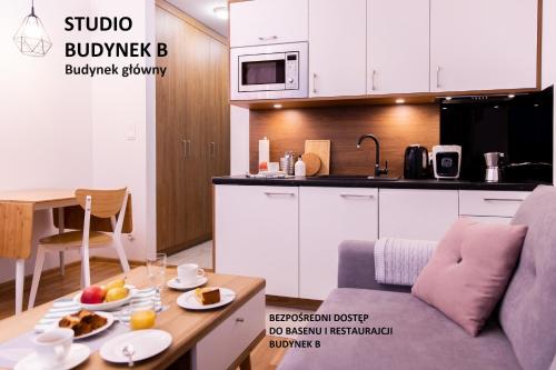 薩比諾沃的住宿－BalticSea Apartamenty，厨房配有沙发和餐桌,上面摆放着食物