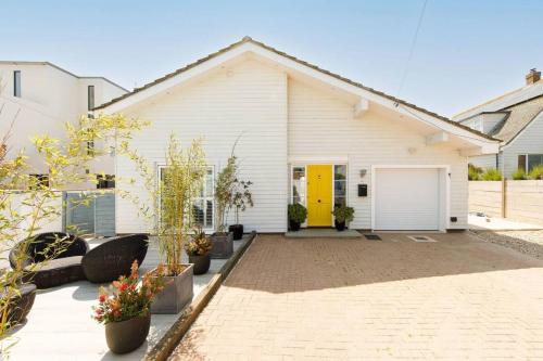 una casa blanca con puerta amarilla en The Kite House en East Wittering