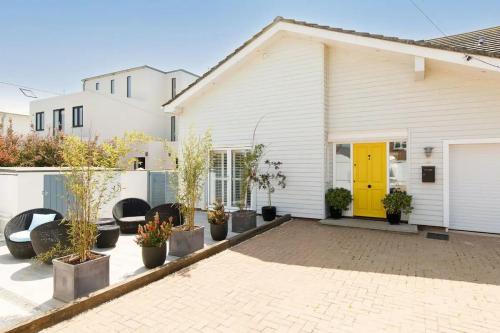 a white house with a yellow door and potted plants at The Kite House in East Wittering